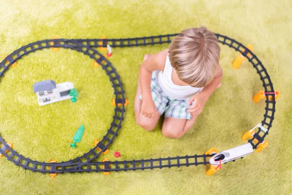 Lindo niño jugando con juguete ferrocarril carretera en casa en el suelo . — Foto de Stock