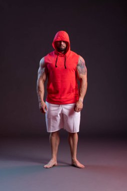 Kırmızı kazaklı güçlü kaslı adam poz veriyor..