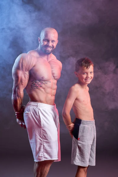 身强体壮的男人赤身裸体地和儿子在工作室里摆出一副红蓝相间的姿势 — 图库照片