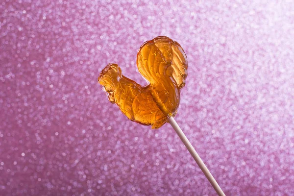 Bokeh defocused ışıklar ile pembe soyut arka planda bir sopa şeker Lollipop horoz