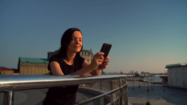 Vrolijke vrouw een bericht te typen op de zonsondergang — Stockvideo