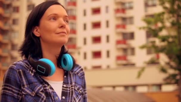 Morena hembra está usando auriculares azules en el distrito moderno — Vídeo de stock