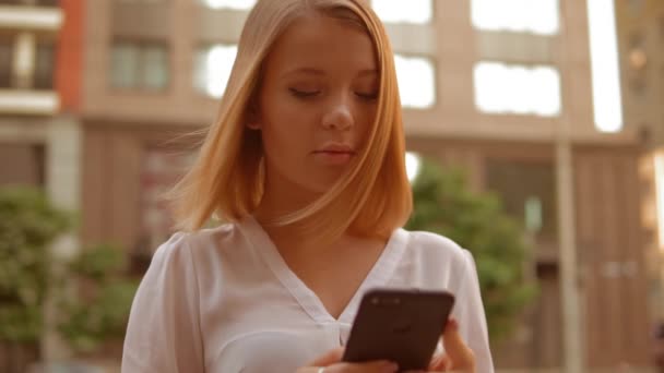 Mujer caucásica utilizando el teléfono móvil al aire libre — Vídeo de stock