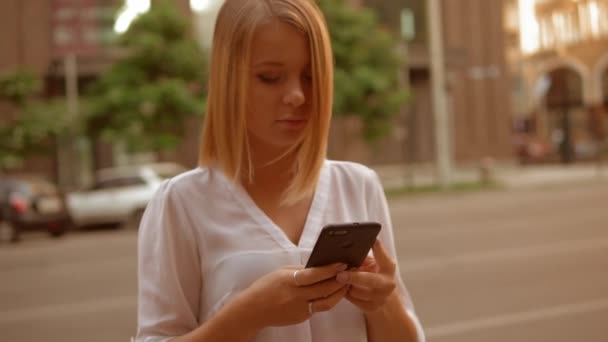 Блондинка-портретистка держит мобильный телефон на улице — стоковое видео