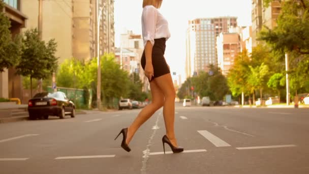 ブロンドの髪を身に着けている白いシャツと黒いスカートとハイヒール靴の夏 City Slow モーションでは 道路の上を歩く側ビュー ファッショナブルな女性 — ストック動画