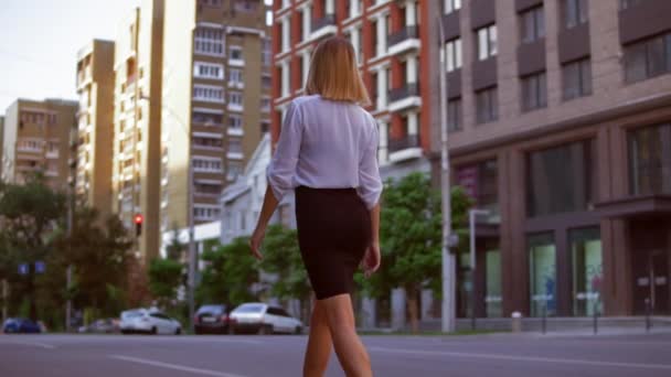 Mujer con cabello rubio camina por la calle — Vídeos de Stock