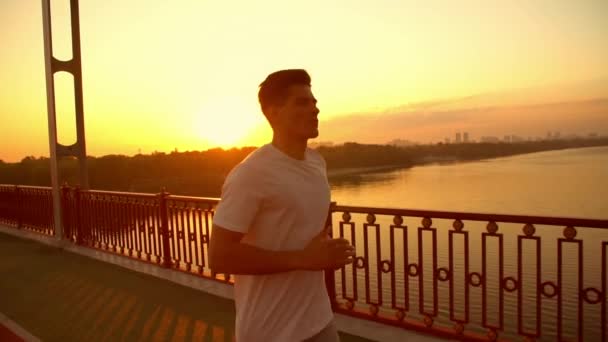 Atlético homem correndo durante o pôr do sol — Vídeo de Stock