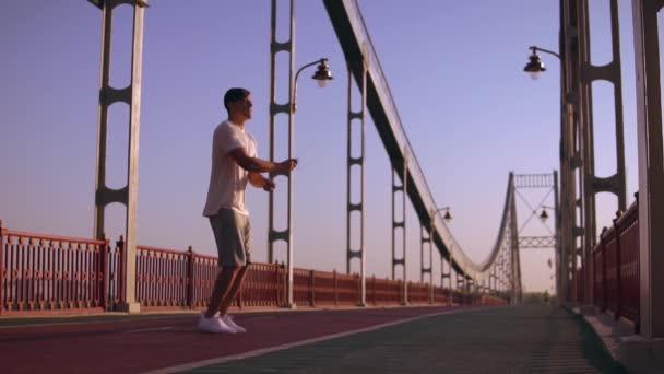 Seitenansicht eines Mannes, der auf die Brücke springt — Stockvideo