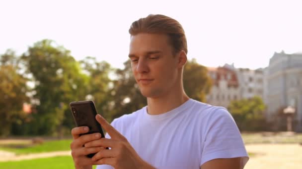 Rättvis haired kille chattar använda telefonen — Stockvideo