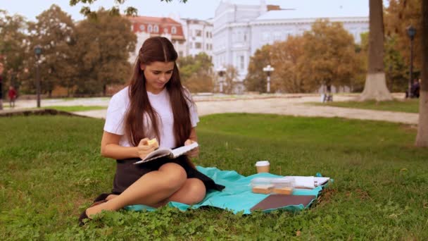 Attraktiv tjej läser roman utomhus — Stockvideo