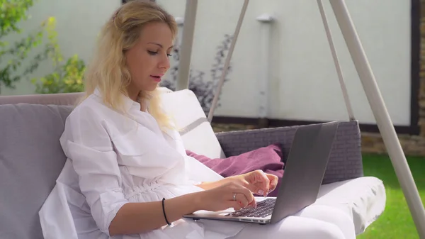 Attraktive erwachsene Frau sitzt mit Laptop auf Schaukel. — Stockfoto