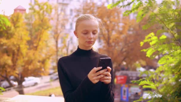 Jeune fille caucasienne bavarder en ligne à l'extérieur — Video