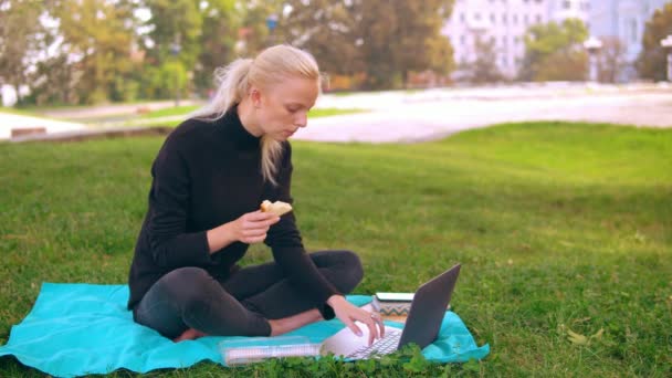 Kaukázusi lány szendvicset eszik a szabadban — Stock videók