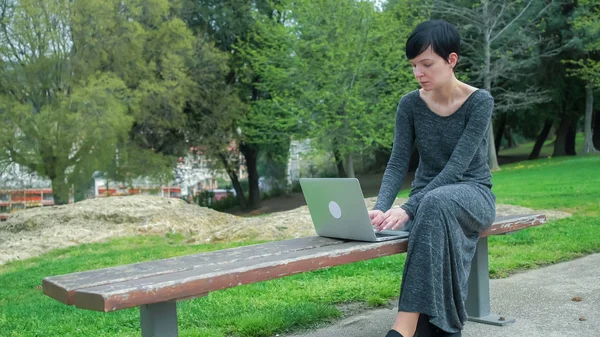 Geschäftsfrau arbeitet im Park am Computer. — Stockfoto