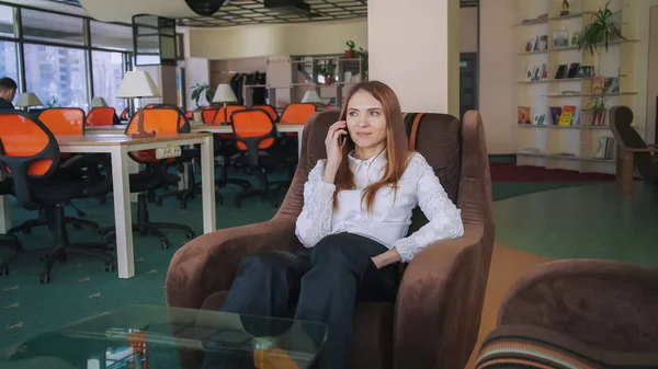 Donna d'affari che parla al telefono seduta su una poltrona — Foto Stock