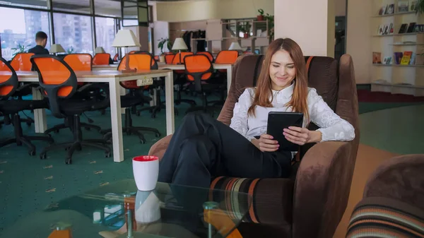 Donna al lavoro guardando la foto sulla tavoletta e ridere . — Foto Stock