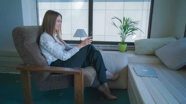 Gelukkig zakenvrouw zittend op de fauteuil met een tablet heeft een pauze — Stockfoto