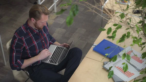 Бородатий чоловік п'є каву і подорожувати по Інтернету під час відпочинку на стілець — стокове фото