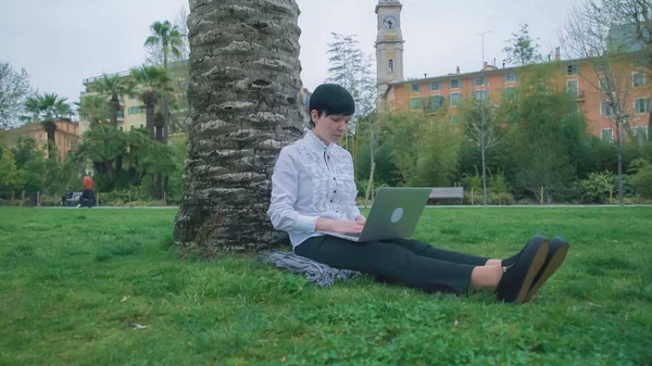 Frau arbeitet im Park unter freiem Himmel am Computer. — Stockfoto