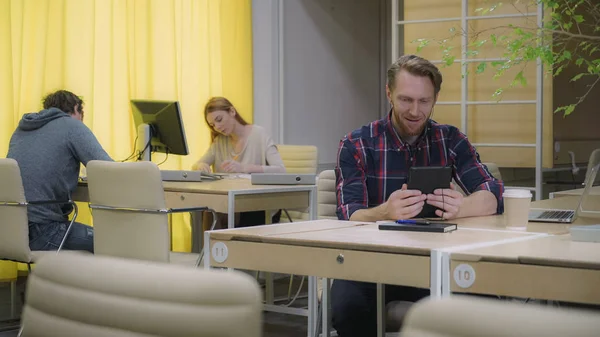 La gente del espacio abierto trabaja, el hombre con auriculares habla con una tableta . — Foto de Stock