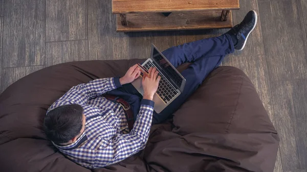 Homme attrayant couché sur une chaise et acheter en ligne avec une carte de crédit . — Photo