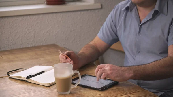 Middle-aged man pays bills over the Internet in the hands of the credit card.