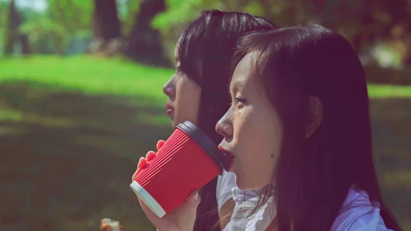 Ženy jíst rohlík, směje se na čerstvém vzduchu. — Stock fotografie