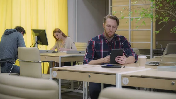 La gente del espacio abierto trabaja, el hombre con auriculares habla con una tableta . — Foto de Stock