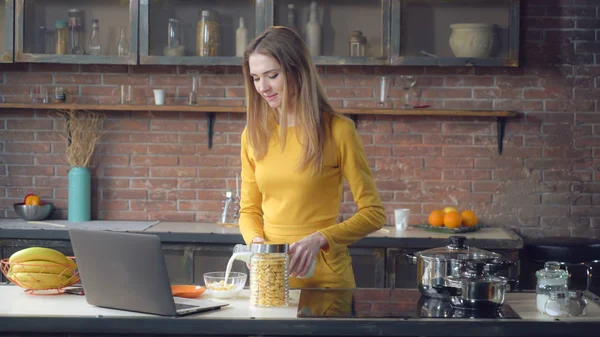 컴퓨터를 사용 하 여 아파트에서 아침 식사를 준비 하는 여자. — 스톡 사진