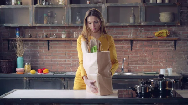 Femme avec de la nourriture dans un sac en papier dans un appartement . — Photo