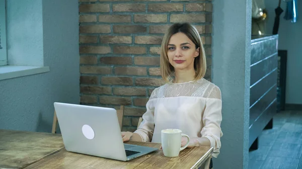 Jonge vrouw kantoorbediende te typen op de computer en het drinken van koffie — Stockfoto