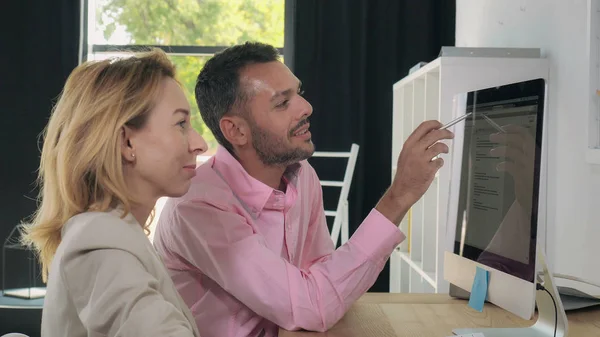 Compañeros de trabajo hablando y sonriendo cerca de pc . — Foto de Stock