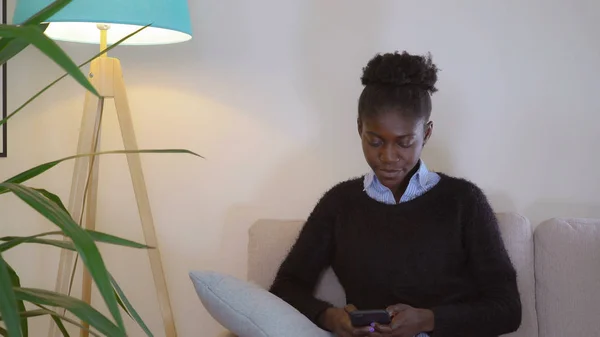 Afrikai lány SMS üzenetet otthon. — Stock Fotó