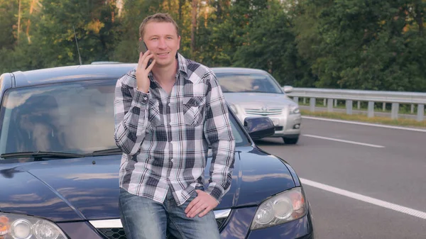 Dospělý chlap za auto volání služby zákazníkům. — Stock fotografie