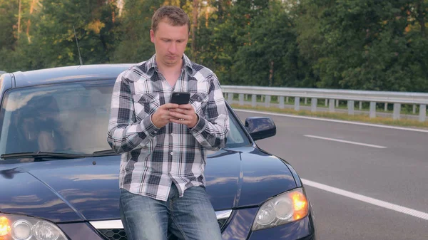 Guy po dopravní nehodě na příjezdové cestě, zprávy na mobil. — Stock fotografie