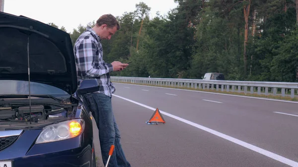 Kavkazská chlapík poblíž silnice rozbité auto. — Stock fotografie