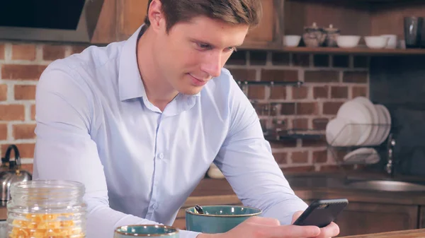 L'homme prend son petit déjeuner et utilise son téléphone intelligent. — Photo