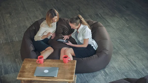 Twee vrouwen zittend op de Bank in het café met behulp van Tablet PC — Stockfoto