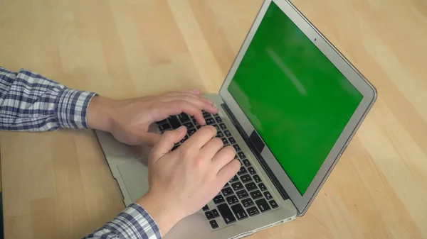 Чоловічі руки, які друкують на ноутбуці з зеленим екраном . — стокове фото