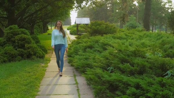 Mladá dívka jde na trati v letním parku úsměvu a radosti. — Stock fotografie