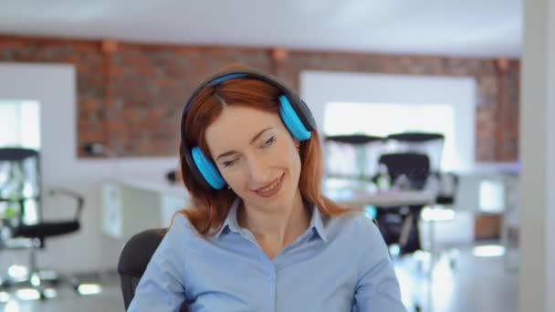 Rothaarige Geschäftsfrau hört Musik bei der Arbeit — Stockvideo