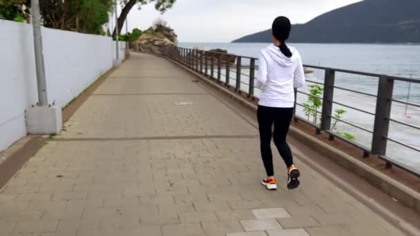Woman jogging along seashore 4k video — 비디오