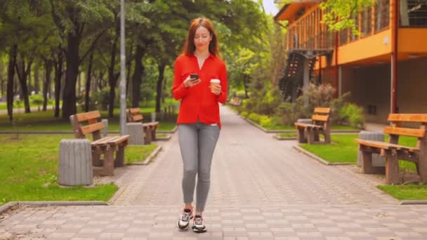 Dame met smartphone lopen over de weg op straat — Stockvideo