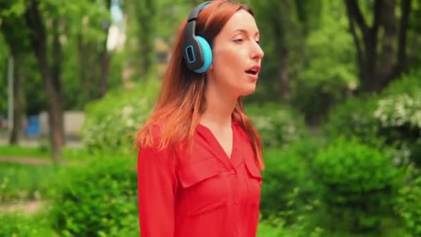 Young Girl Écoute de la musique dans les écouteurs et les promenades — Video