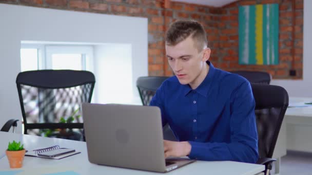 Młody człowiek praca na laptop w Loft stylizowany biuro. — Wideo stockowe