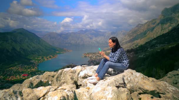 Femme d'âge moyen assise au sommet de la montagne et parlant par smartphone — Video