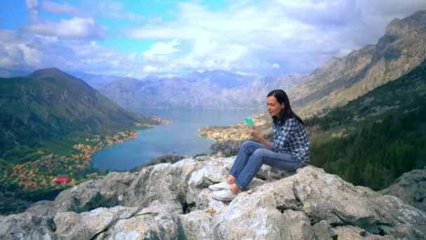 Mujer joven Mirando en el teléfono inteligente en pico de montaña — Vídeos de Stock