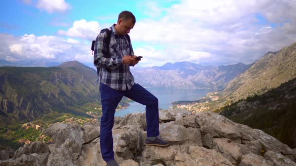 Hiker stoi na szczycie patrząc na góry — Wideo stockowe