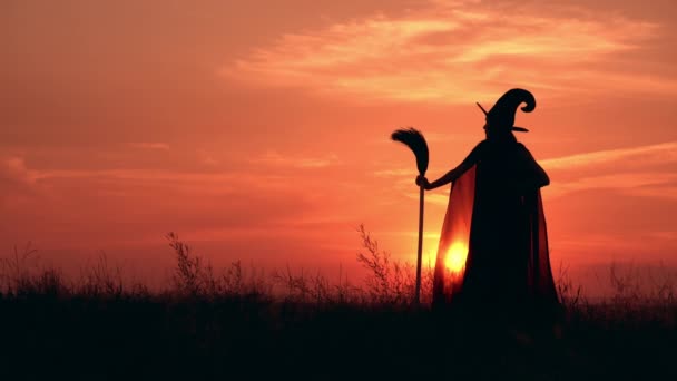 Bruxa segurando vassoura posando ao ar livre ao nascer do sol — Vídeo de Stock