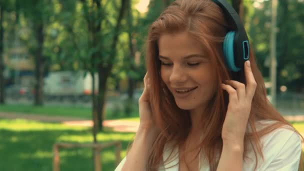 Dívka se zobrazením na boku s využitím sluchátek venku — Stock video